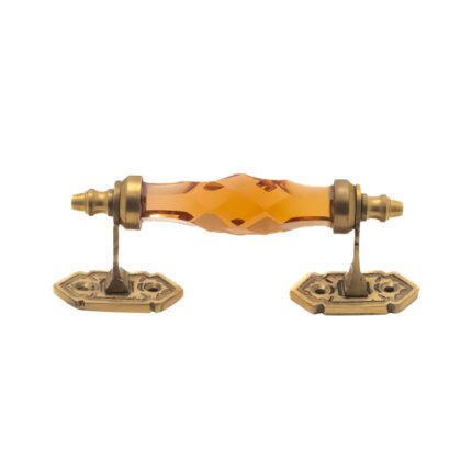 Golden amber crystal and brass pull handle with center on a dark wood cabinet